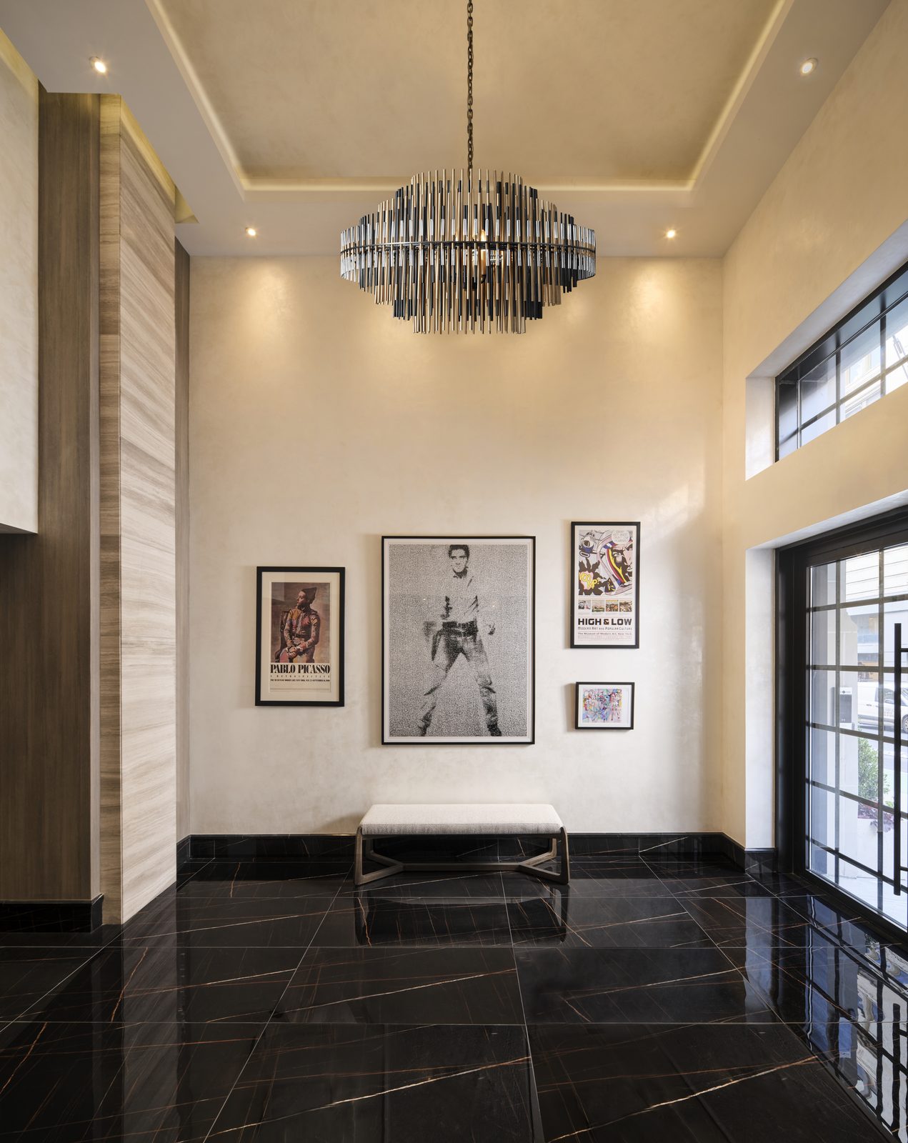Archive Lofts lobby with framed museum exhibition posters and a sculptural chandelier